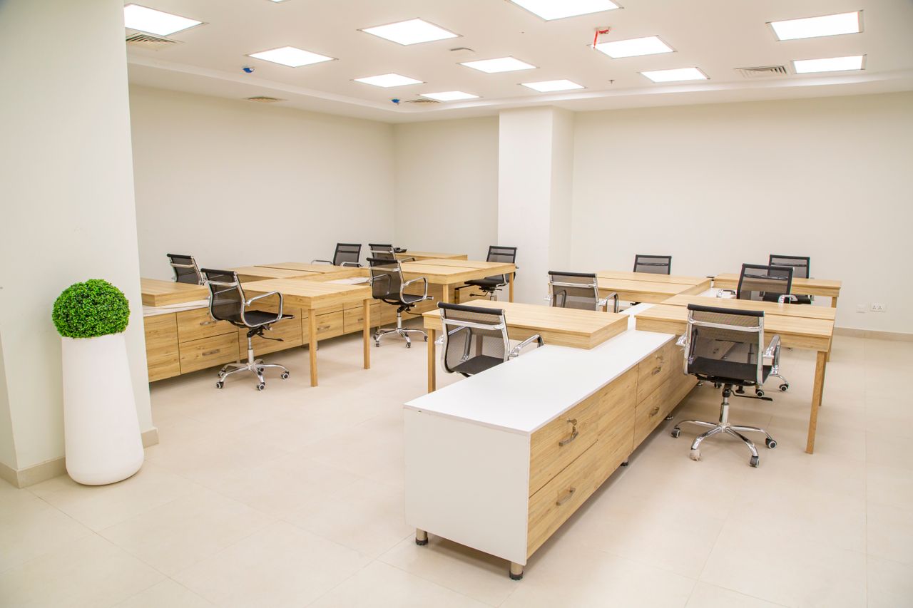 our-story A bright, modern office space featuring wooden desks, rolling chairs, and ample lighting.